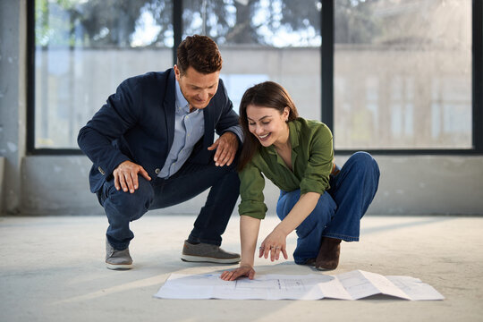 Happy young couple examining blueprints together during their home renovation project