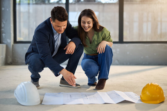 Happy couple analyzing plans at their renovating apartment