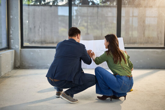Happy young couple examining blueprints together during their home renovation project