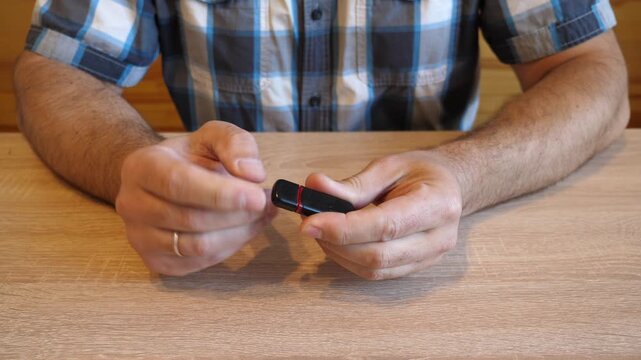A man inserts and removes the cap of a USB flash drive, creating a distinctive snap sound. The video contains clean original audio.