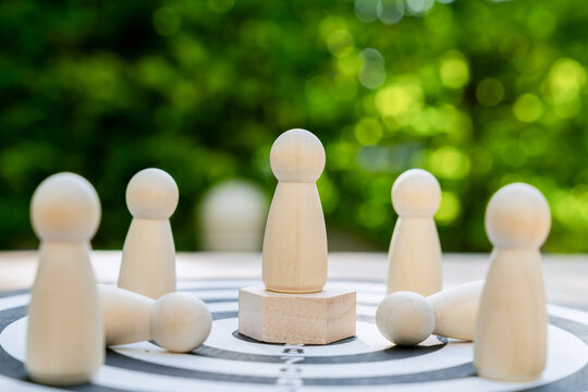 Wooden figure on a platform and dartboard a leadership concept representing the achievement of goals.