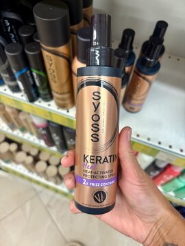Woman Holding Syoss Keratin Heat Protect Spray Bottle
