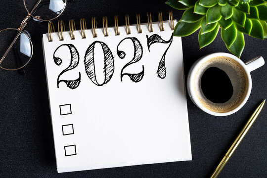 2027 New year resolutions on desk. 2027 goals list with notebook, coffee cup, plant on black table. Resolutions, plan, goals, action, checklist, idea concept. New Year 2027 resolutions. Copy space