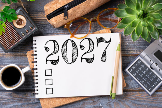 New year resolutions 2027 on desk. 2027 goals list with notebook, coffee cup, plant on wooden table. Resolutions, plan, goals, action, checklist, idea concept. New Year 2027 resolutions, copy space