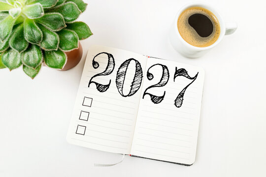 New year resolutions 2027 on white desk. 2027 resolutions list with notebook, coffee cup on table. Goals, resolutions, plan, action, checklist concept. New Year 2027 template, copy space