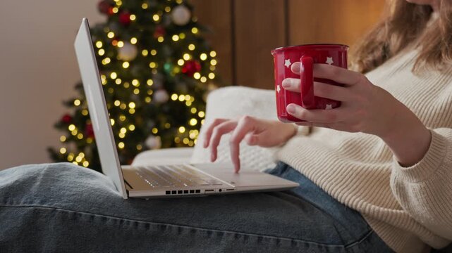 Woman Using Laptop with Hot Drink During Cozy Christmas Evening