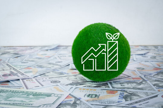 Green investment and sustainable finance concept. Moss sphere with growth chart graphic on a pile of US dollar banknotes. ESG investing, eco economy and financial return.