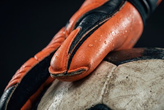 Goalkeeper glove on soccer ball wet texture dramatic sport training