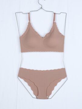 Women seamless lingerie set with bra and panties on metal wire hanger isolated on white background.