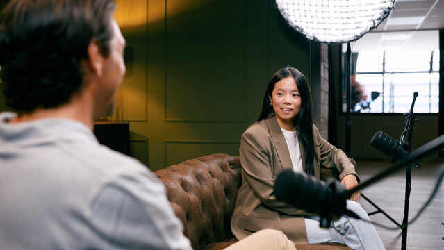 Young woman collaborating with a content creator on a podcast episode, discussing topics in a modern recording studio