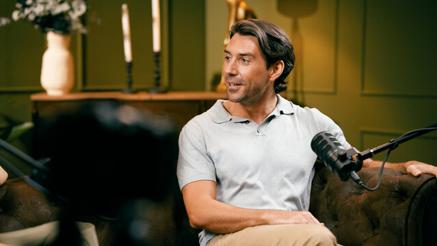 Man recording an audio podcast, speaking into a microphone during an interview in a studio setting, sharing his content