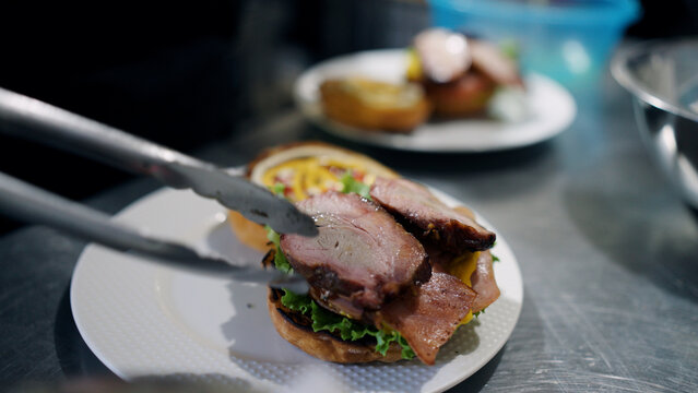 Chef assembling a delicious pork sandwich with fresh ingredients and grilled meat, representing street food culture and local grills