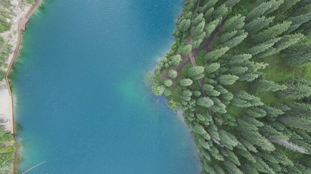 Top-down view of a clear turquoise lake bordered by dense pine trees.