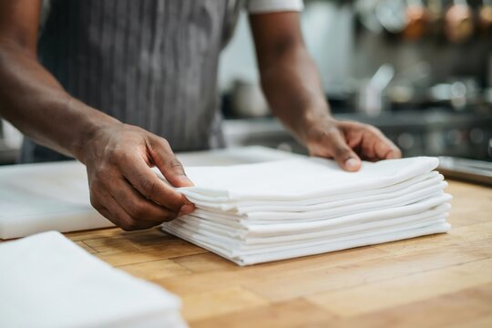 A chef prepares a stack of white kitchen towels. Professional food safety.