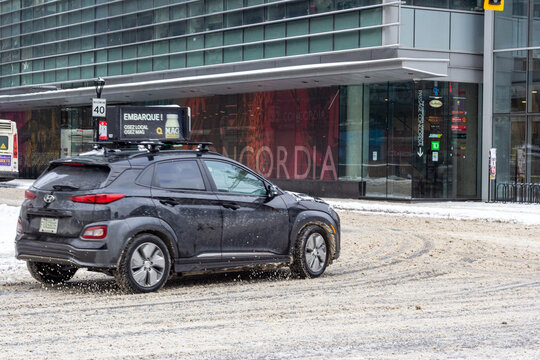MONTREAL, CANADA, 25 December 2025 : Winter city traffic, electric car, snow-covered street, urban scene, digital billboard, modern architecture