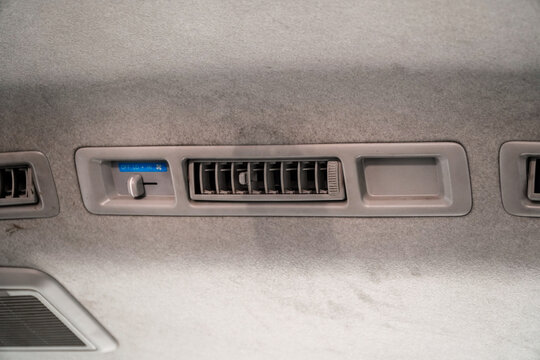 Close-up of car interior air vent control panel with fabric ceiling and climate settings for vehicle comfort, ideal for automotive design or travel interiors, elegantly showcasing dashboard.
