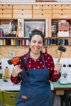 Craftswoman holding pneumatic stapler and rubber mallet