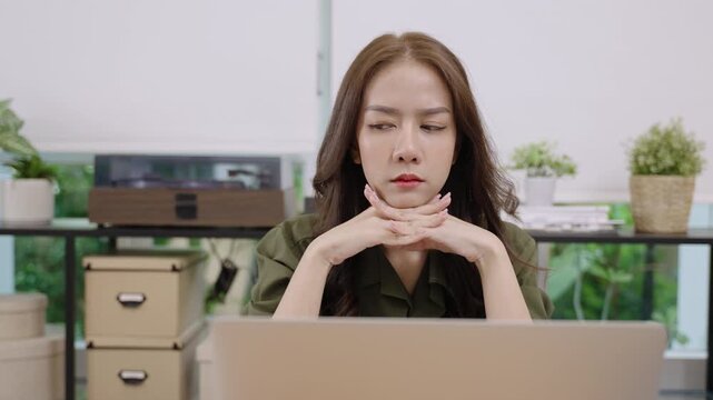 Attractive Asian business woman sitting using laptop while thoughtful, inspiration, and having good ideas in office. Happy excited young female freelance with thinking and typing on notebook computer.