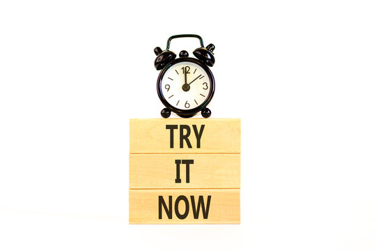 Try it now words symbol. Concept words Try is now on beautiful wooden blocks. Beautiful white background. Black alarm clock. Business support motivational and try is now concept. Copy space.