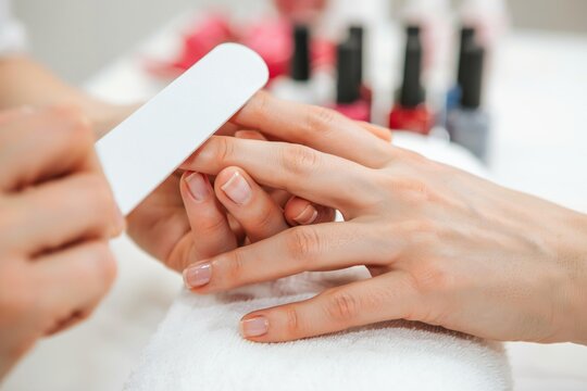 A manicurist files fingernails. Professional salon care concept.