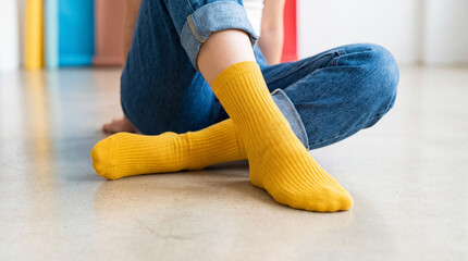 Fototapeta premium Person wearing vibrant yellow socks and blue jeans sitting on floor, enjoying comfort and leisure