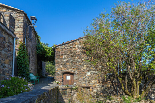 Traditional schist stone houses line a sunny narrow alley