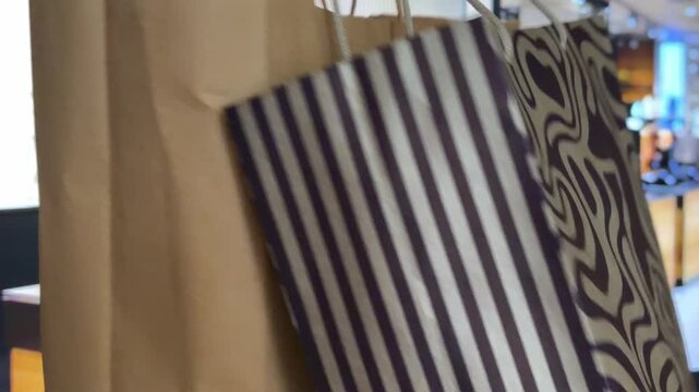 Shopping bags swinging in a modern mall with a customer walking through the store after a successful purchase, showing consumerism, retail therapy, and lifestyle concepts