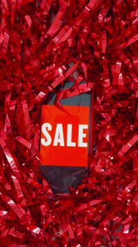 Sale shopping bag appearing through shiny red tinsel during black friday, christmas, or valentine's day celebrations, announcing special offers and discounts