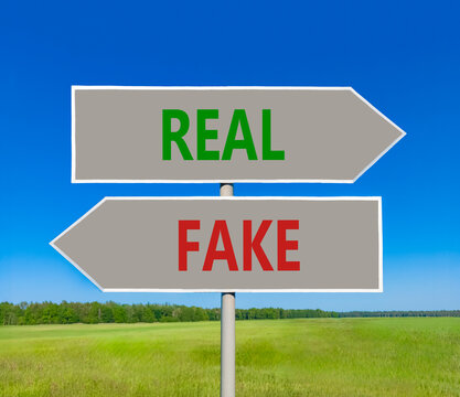 Real or fake words symbol. Concept words Fake and Real on beautiful grey road sign. Beautiful blue sky background. Business and real or fake concept. Copy space.