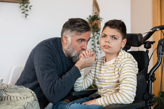 Father kissing son's hand providing support and care