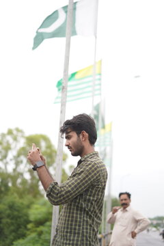 A man taking picture in front of Pakistan flag with Kashmir flag waving together outdoors unity and solidarity