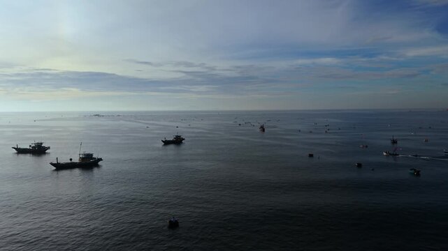 Cinematic aerial drone footage capturing dozens of fishing boats scattered across the calm sea during soft morning light in Vietnam. Ideal for travel, maritime industry, fishing, coastal landscape, tr