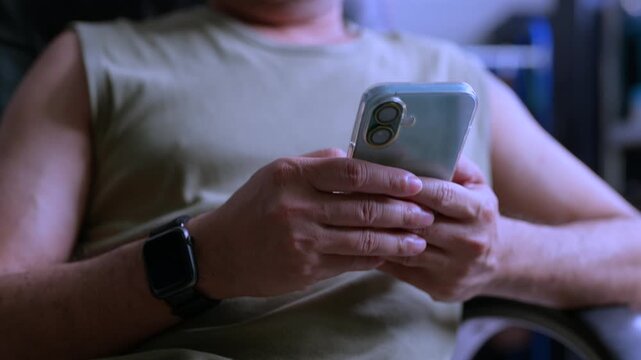 Man holding phone, checking messages, typing text, operating touchscreen, browsing internet, reviewing application, managing schedule, communicating online, wearing smartwatch.
