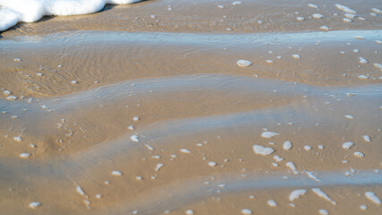 Close-up of wet sand ripples and sea foam texture, Australia © The Long Horizon