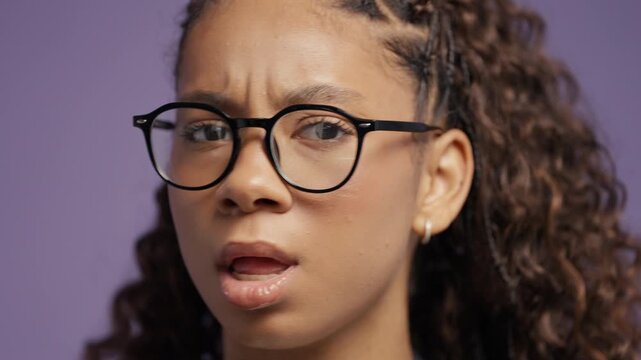 Young african teenage girl shaking head to say no in studio portrait on violet background. Disagreement, rejection, refusal, negative response, decision making and communication.