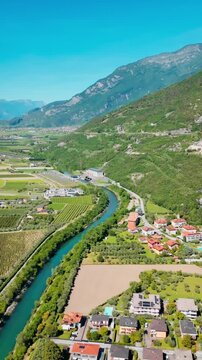 Mountain valley landscape near Lake Garda with river and farmland. Green fields, rural settlement and alpine terrain in northern Italy