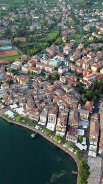Aerial view of Garda town on the shore of Lake Garda in northern Italy, with colorful houses and mountains in the background