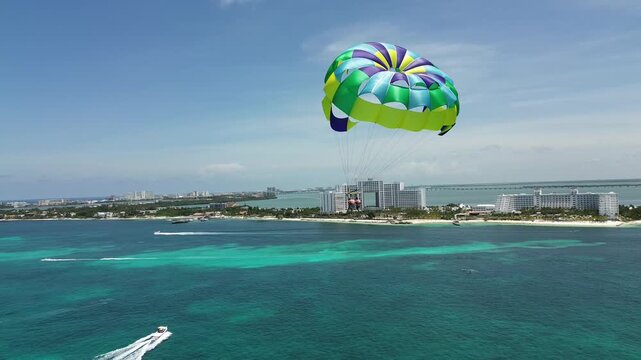 Parasailing in the middle of the sea on a beautiful, sunny day over the blue waters of Canc&uacute;n, Quintana Roo, Mexico drone shot.