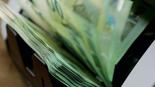 Euro banknotes passing through an automatic money counter before currency exchange. International finance, travel money and foreign exchange services