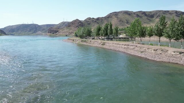 Aerial drone flight over the turquoise Ili River in Kazakhstan