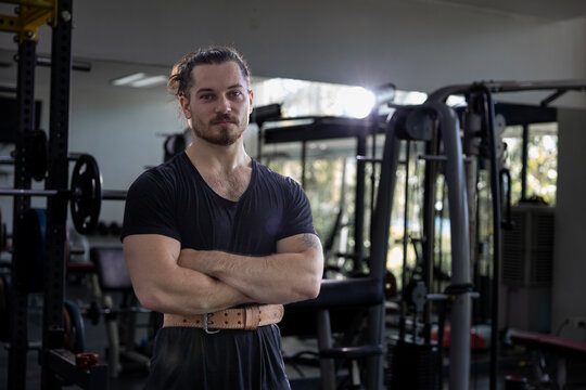 Portrait of caucasian muscular man with perfect abs and bicep muscle inside gym with dark background for exercise and workout in high contrast low key lighting studio