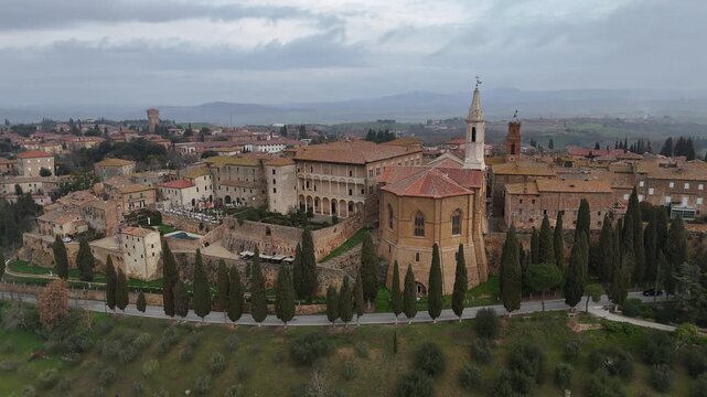 Drone horizontal panning shot moving right to left behind the historic Pienza Cathedral architecture