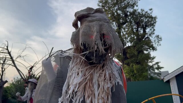 Creepy scarecrow animatronic with glowing red eyes turning from side to side at a haunted Halloween attraction.