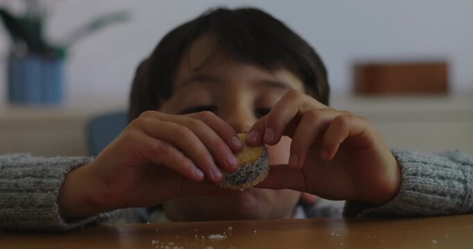 Young boy grabs coconut dessert and takes a bite at home kitchen table, satisfying curiosity with playful appetite, sweet enjoyment and authentic childhood spontaneity