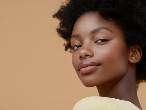 Young Black woman with natural afro hair and glowing skin smiles gently