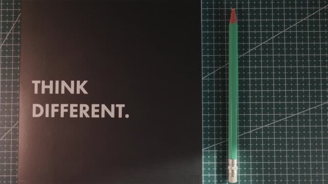Wide creative workspace shot with Think Different notebook