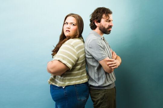 Upset couple standing back to back looking stubborn, experiencing relationship conflict and disagreement