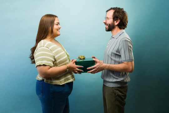 Profile view of a couple exchanging a present, celebrating special occasion, showing surprise and gratitude