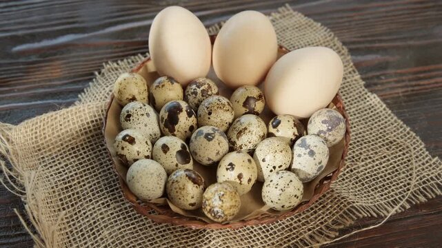 Fresh quail and chicken eggs in a plate on a wooden table in a rustic background, farm organic food product
