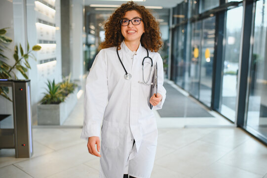 Female doctor walking smiling in hospital corridor
